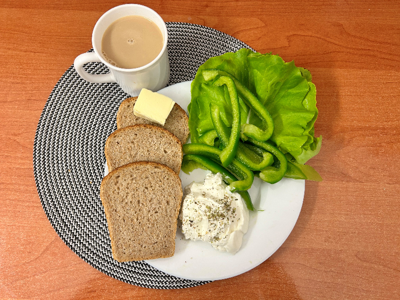 Na zdjęciu: Kawa z mlekiem, Chleb Graham, Masło extra 82%, Serek homo o smaku naturalnym z ziołami, Papryka świeża, Sałata zielona